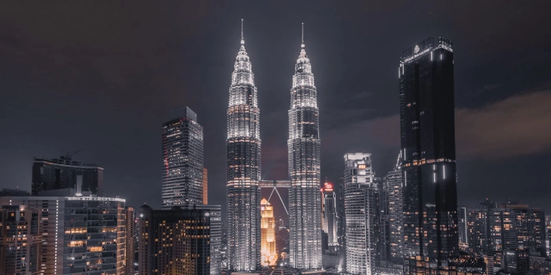 Petronas Twin Towers shining at night with surrounding skyscrapers in Malaysia