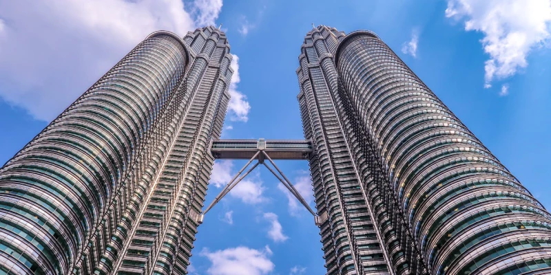 Petronas Twin Towers in Kuala Lumpur illuminated against a vibrant evening sky